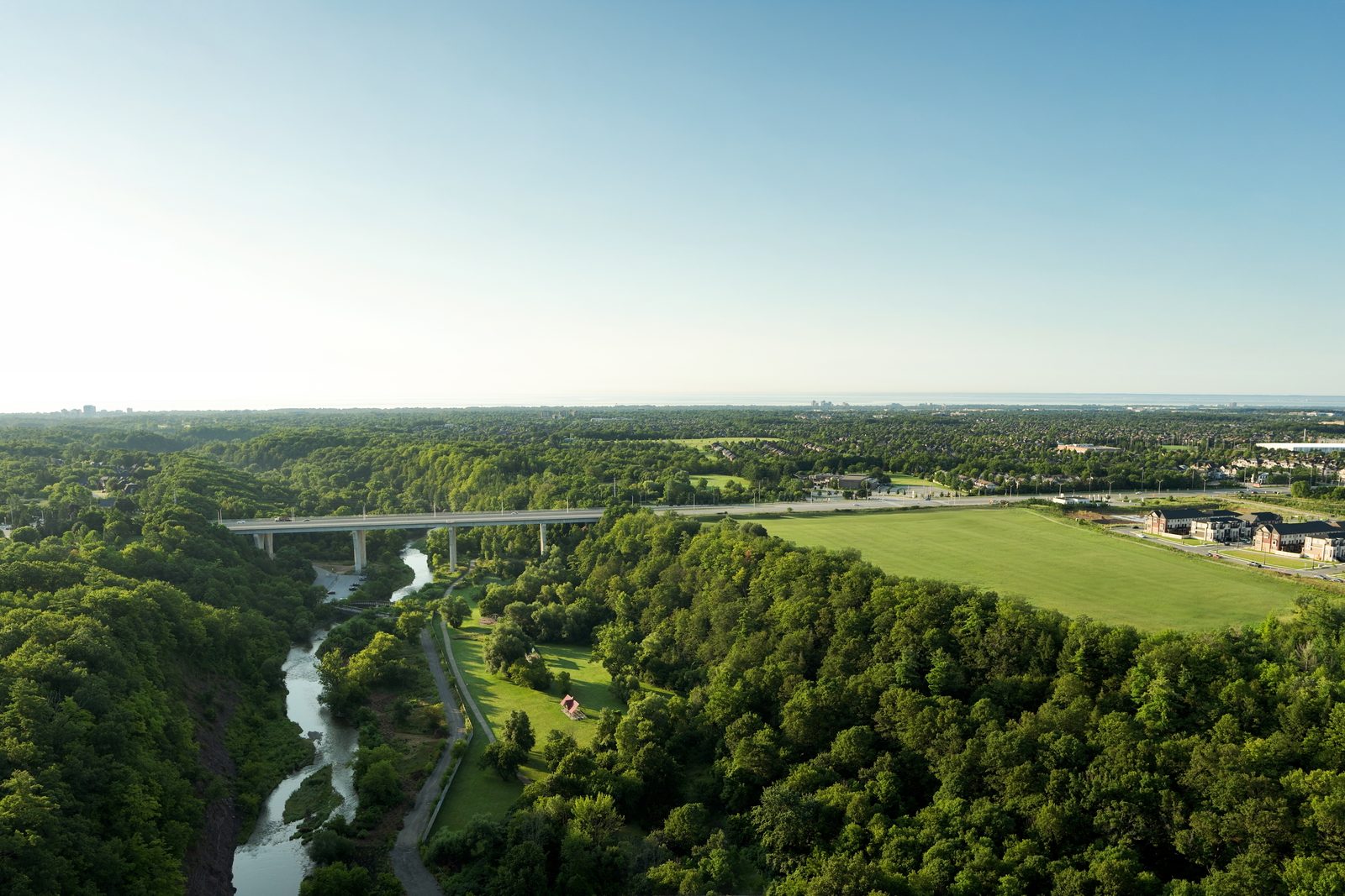 Aerial view of Sixteen Mile Creek and Lions Valley Park beside the Five Oaks community site in Oakville, with Lake Ontario on the horizon